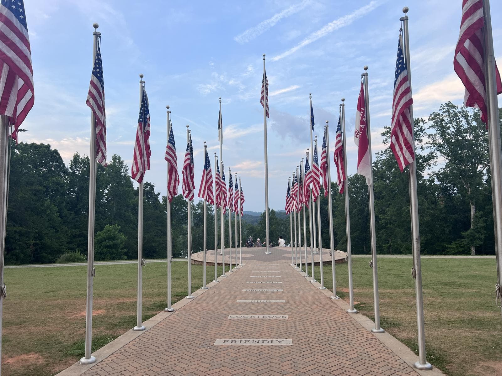 A row of American flags lining a brick path at dusk