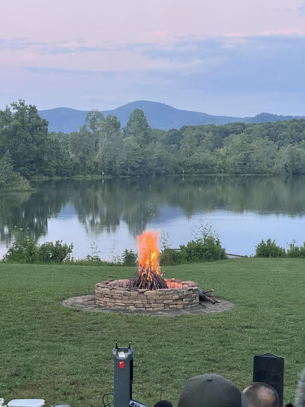 A campfire burning at dusk beside a still lake