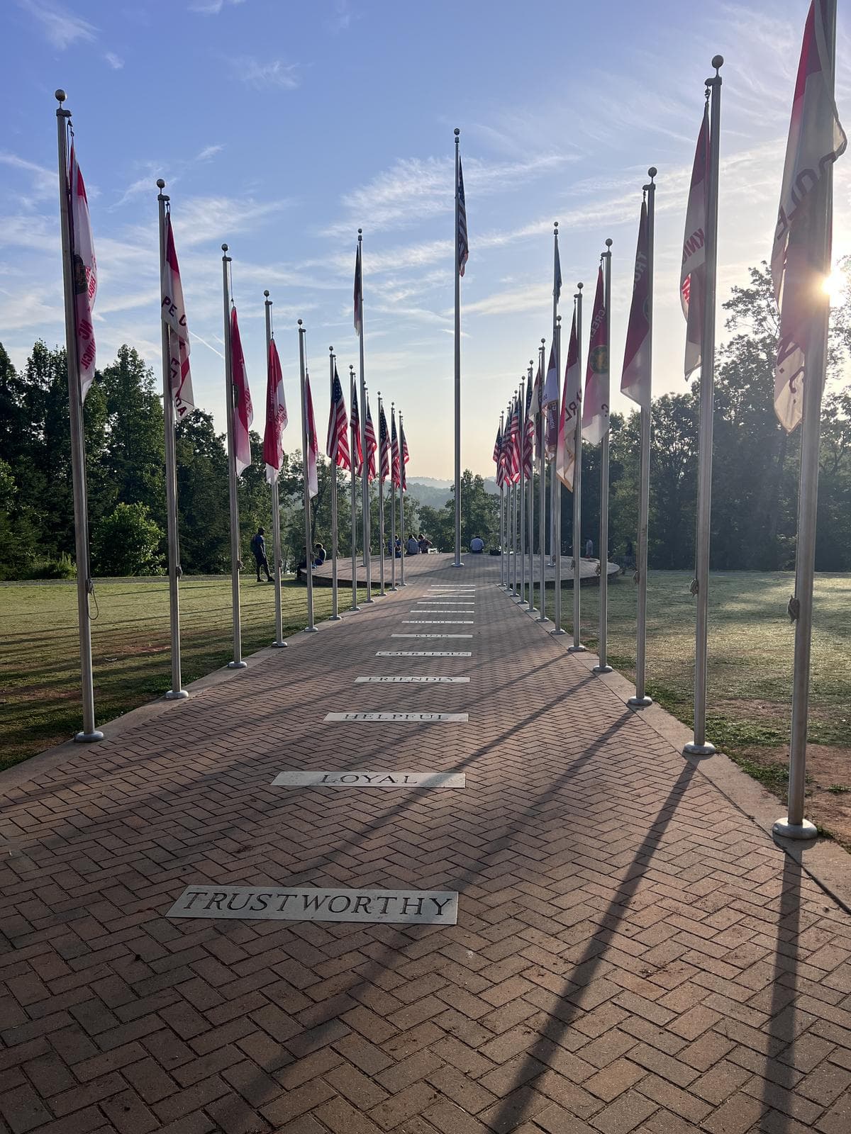 A brick path lined with flags, each paving stone stamped with a point of the Scout Law